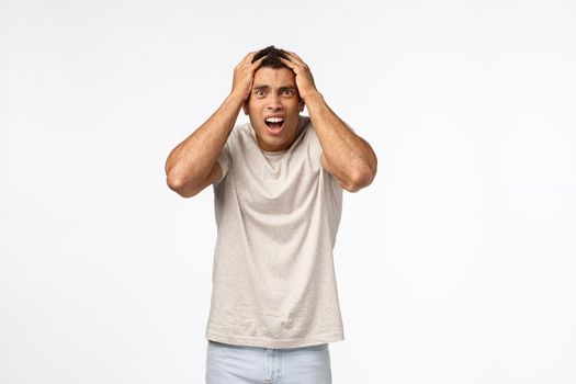 Man in panic feeling frustrated, alarmed, grab head staring upset camera, gasping drop jaw, cant believe failed test, grimacing bothered, lost competition, feel let down and gloomy, white background.