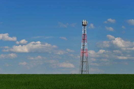Transmitter for gsm signal of mobile phones in the field. In the background blue sky with clouds. Concept for modern technology and industry - Telecommunication Tower.