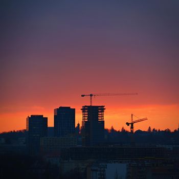 Construction of buildings with a crane, workers and construction machinery at sunset. Concept for construction and industry.