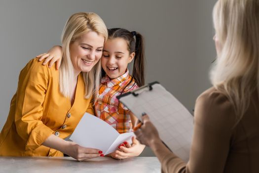 Hand of a professional family psychotherapist writing notes in front of a family with a child during a consultation.