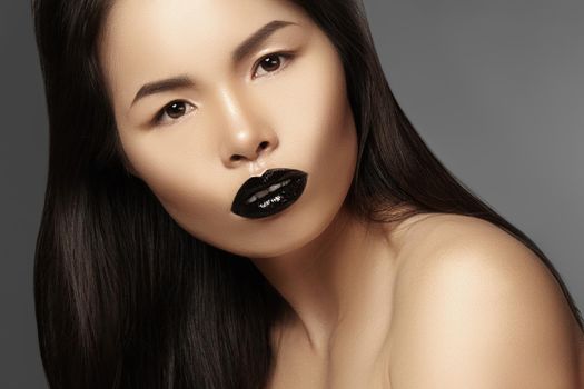 High Fashion Beauty Asian Model with bright Lip Gloss Make-up. Black Lips with gloss lipstick makeup. Long dark hair. Horisontal photo