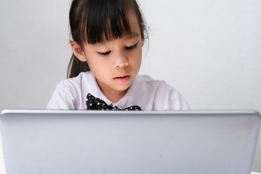 Cute Asian little girl playing teacher role game or a small businesswoman working with laptop in the office. Homeschool children's play and learning.