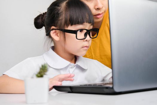 Mother teaches her daughter the basics of business. Little businesswoman with laptop working in office with mother. Children and business concepts