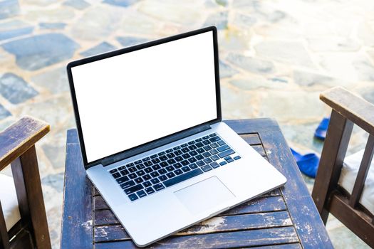 grey laptop computer open with keyboard on wooden deckchair.