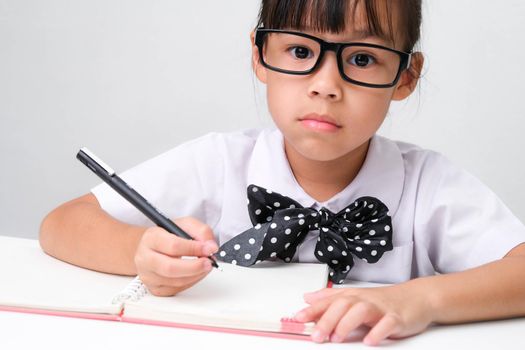 Cute Asian little girl plays teacher role game or little businesswoman taking notes while working in the office. Homeschool children's play and learning.