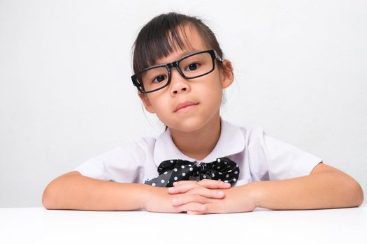 Cute Asian little girl playing teacher role game or a small businesswoman sitting on table in the office and looking at the camera. Homeschool children's play and learning.