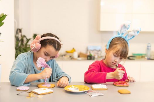 two little sisters decorating homemade cookies in the kitchen at home