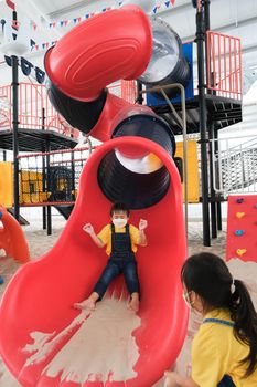 Cute kids playing on the outdoor playground. Little sisters playing slides in the park. Healthy summer activity for children.