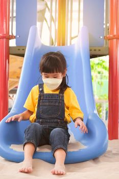 Cute little girl having fun in the outdoor playground. Young girl playing slides in the park. Healthy summer activity for children.