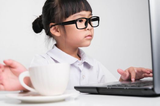 Little businesswoman with laptop working in office with coffee cup on table. children and business concept.