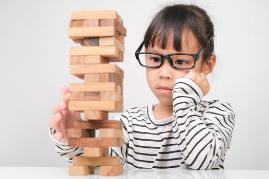 Asian children playing wooden blocks on table at home. Cute little girl having fun playing with building blocks. Wooden block tower building game. Toys for the development of children