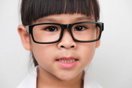 Portrait of a smiling little girl wearing glasses in a doctor or science costume on a white background. Little scientist.