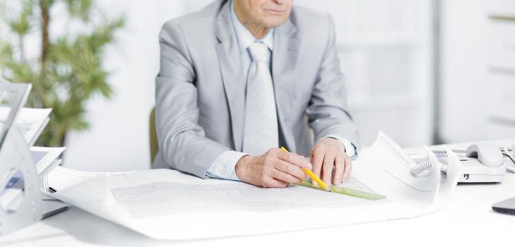 senior engineer works with drawings sitting at his Desk