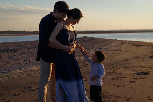 A family with children are walking along a wild evening beach.