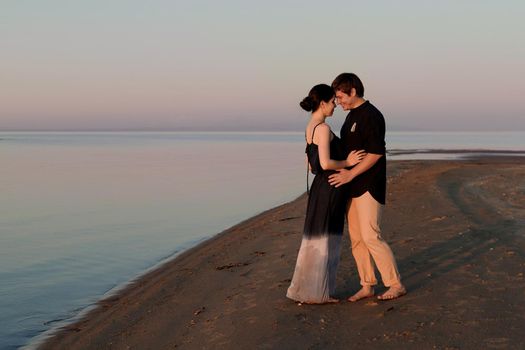 Portrait of a young couple of lovers on the beach in sunset lighting. Copy space.