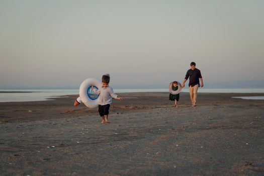 A young father with 2 children returns from the beach in the evening.