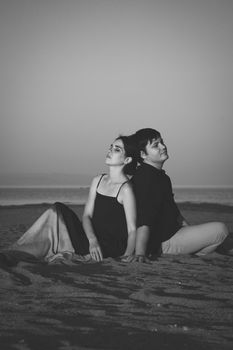Black and white vertical portrait of a young couple of lovers on the beach in sunset lighting. Copy space.