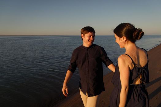 Portrait of a young happy couple in love on the background of the sea in the sunset lighting.