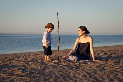 Young mother with little son 3 years old spends time on the beach playing different games.