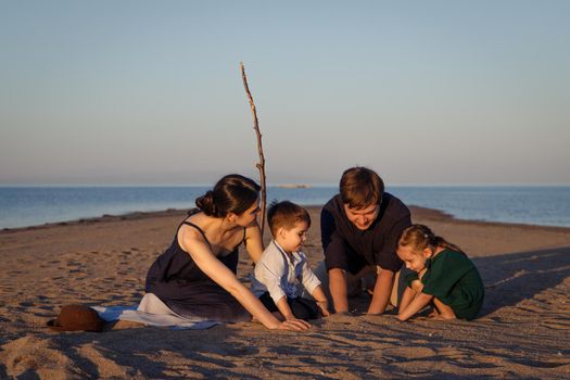 Young family with 2 children playing on the beach in a desert island.