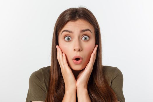 Close-up portrait of surprised beautiful girl holding her head in amazement and open-mouthed. Over white background.