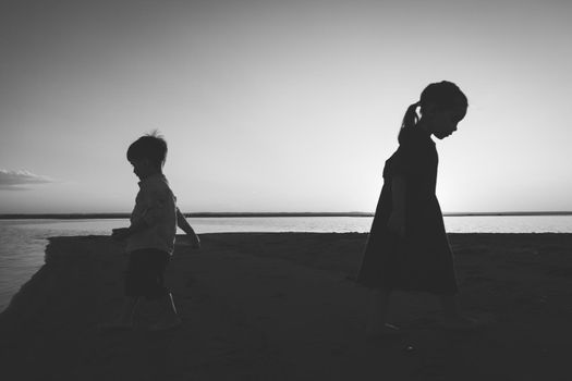 Black and white portrait of two children leaving in different directions outdoor.