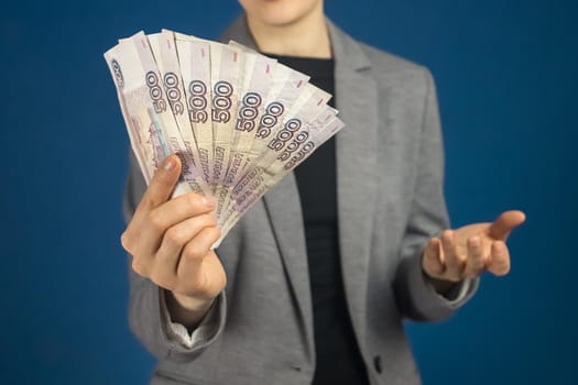 Close-up of Russian ruble bills in the hand of a woman in a gray jacket. Selective focus.