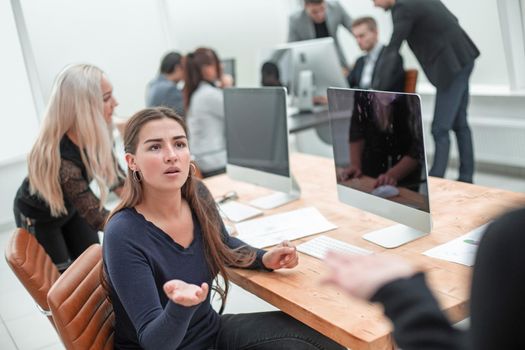 serious young woman asking a question to her colleague. office workdays