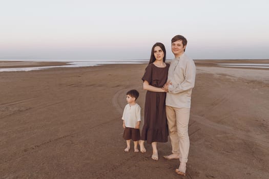 Family look of natural linen clothing on the evening beach. Copy space.