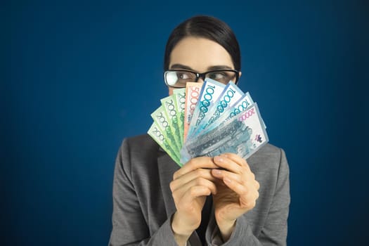 Woman looking sideways above Kazakhstan money tenge in her hands.