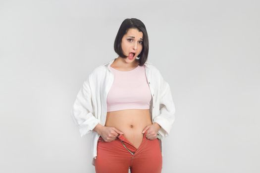 Surprised young woman cannot wear summer pants. Diet, overweight, obesity concept.