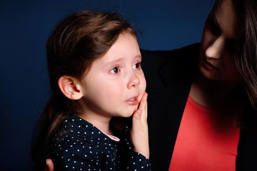 Little girl is upset and crying from resentment in her mother's arms.