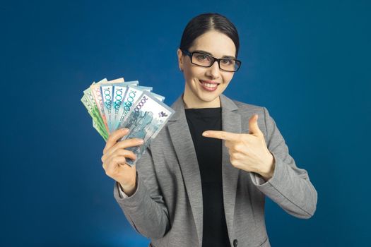 Beautiful young woman in glasses holds a lot of tenge money in her hands.