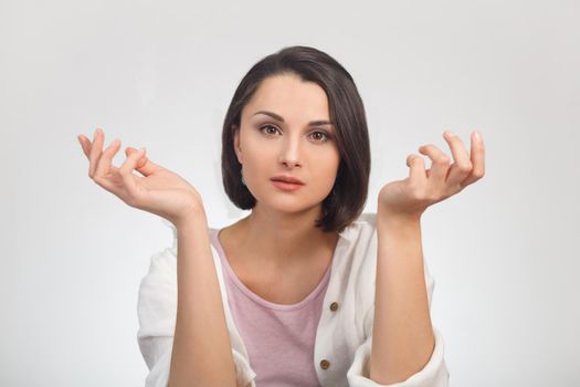 High key portrait of a young woman in light clothing looking at the camera and spreading her arms in different directions.