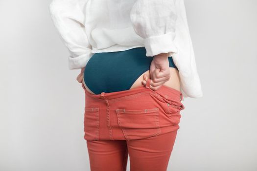 Young woman's bottom doesn't fit in last year's pants. Diet, overweight, obesity concept.