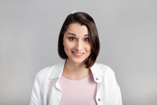 Human face expressions and emotions. Portrait of young brunette woman in pink tank and white shirt looking at camera.