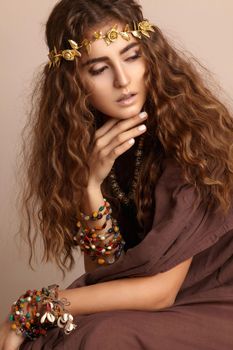 Beautiful Woman. Curly Long Hair. Fashion Model with Healthy Wavy Hairstyle. Accessories. Boho Girl with Autumn Wreath, Gold Floral Crown. Vertical shot