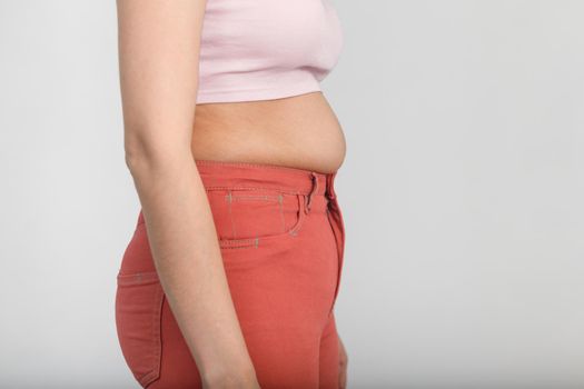 Side view of belly of a slightly overweight young woman. Diet, overweight, obesity concept.