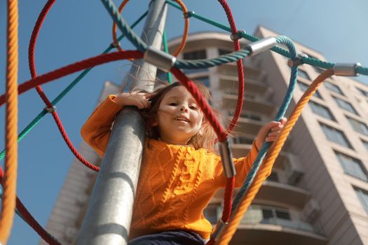 Portrait of a little happy girl on a modern playground in the courtyard of a residential complex.
