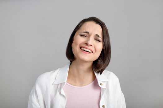 Human face expressions and emotions. Portrait of laughing young brunette multiethnic woman in pink tank and white shirt.