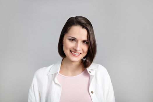 Portrait of smiling young brunette multiethnic woman in pink tank and white shirt.