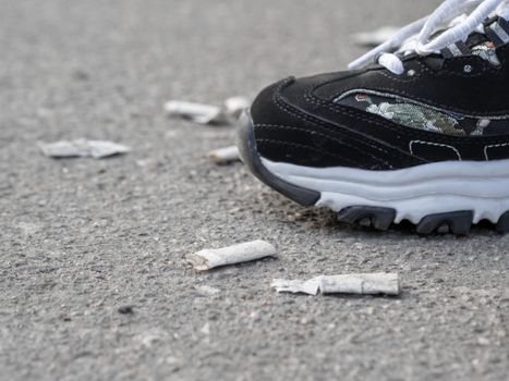 sneakers on cigarette butts on asphalt
