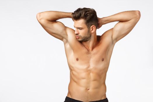 Workout, gym and wellbeing concept. Waist-up attractive sexy young man with naked torso, posing hands behind head, showing strong muscles, perfect body six-packs abdominal abs, bodybuilding concept.