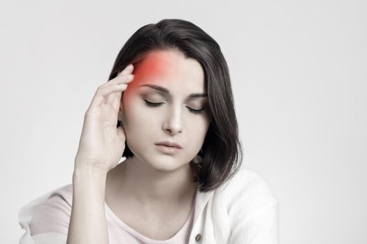 Tired sad brunette woman touches her head, migraine, pain area of red color. Headache concept.