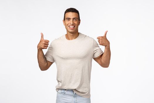 Sounds good. Assertive, optimistic handsome strong man showing thumbs-up. Young athlete agree with new training program, smiling happily, give positive reply, approve awesome idea, white background.
