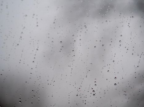 Raindrops on the surface of window glass with a blurred background.