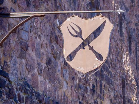 Old metal peeling sign fork with a knife on a stone wall background