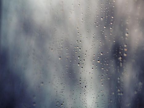 Raindrops on the surface of window glass with a blurred background.