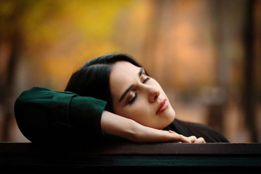 Autumn portrait of young dreaming girl with closed eyes in autumn park.