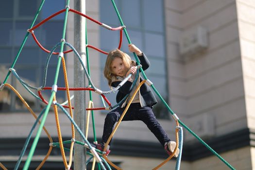 Full of emotion 3-4 years girl playing on the playground on the background of a modern condominium. Selective soft focus.